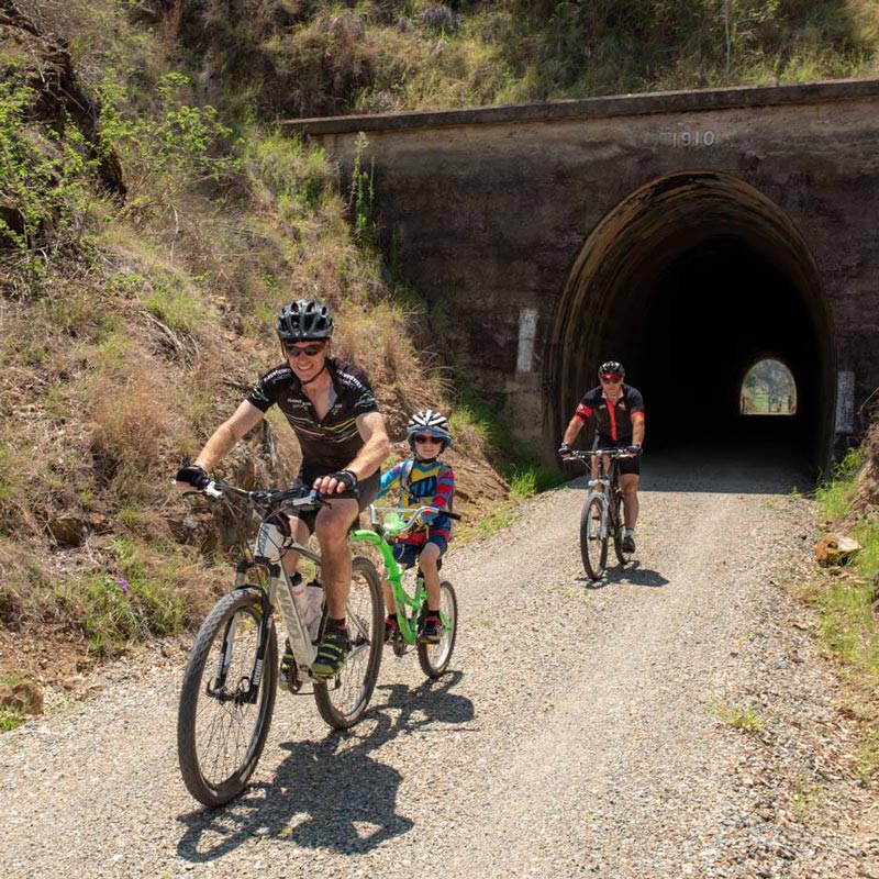 Family riding their bikes through tunnel on Brisbane Valley Rail Trail
